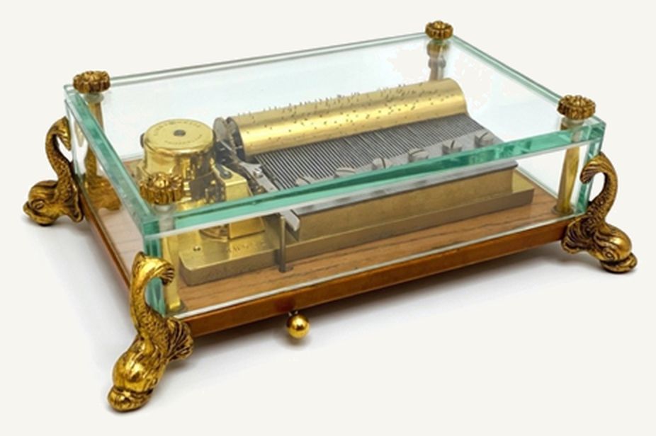 Caja de música Reuge en estuche de cristal biselado con patas de delfín de bronce dorado, con el cilindro de púas y el peine a la vista