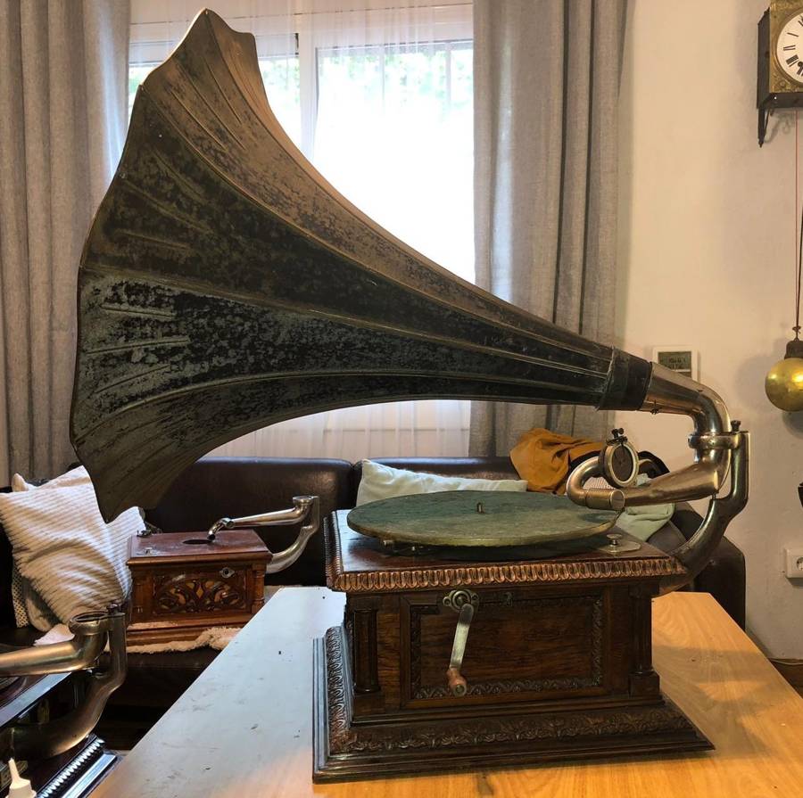 Gramófono HMV con gran bocina metálica oscura sobre un mueble de madera