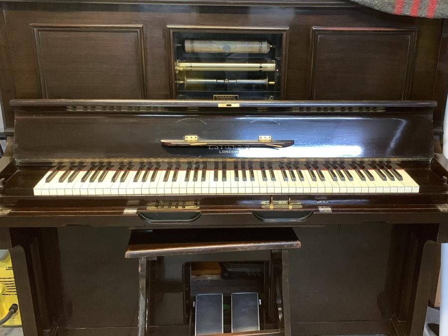 Piano automático Estonola de Londres, con el rollo de papel a la vista tras la portezuela abierta y los pedales del fuelle desplegados